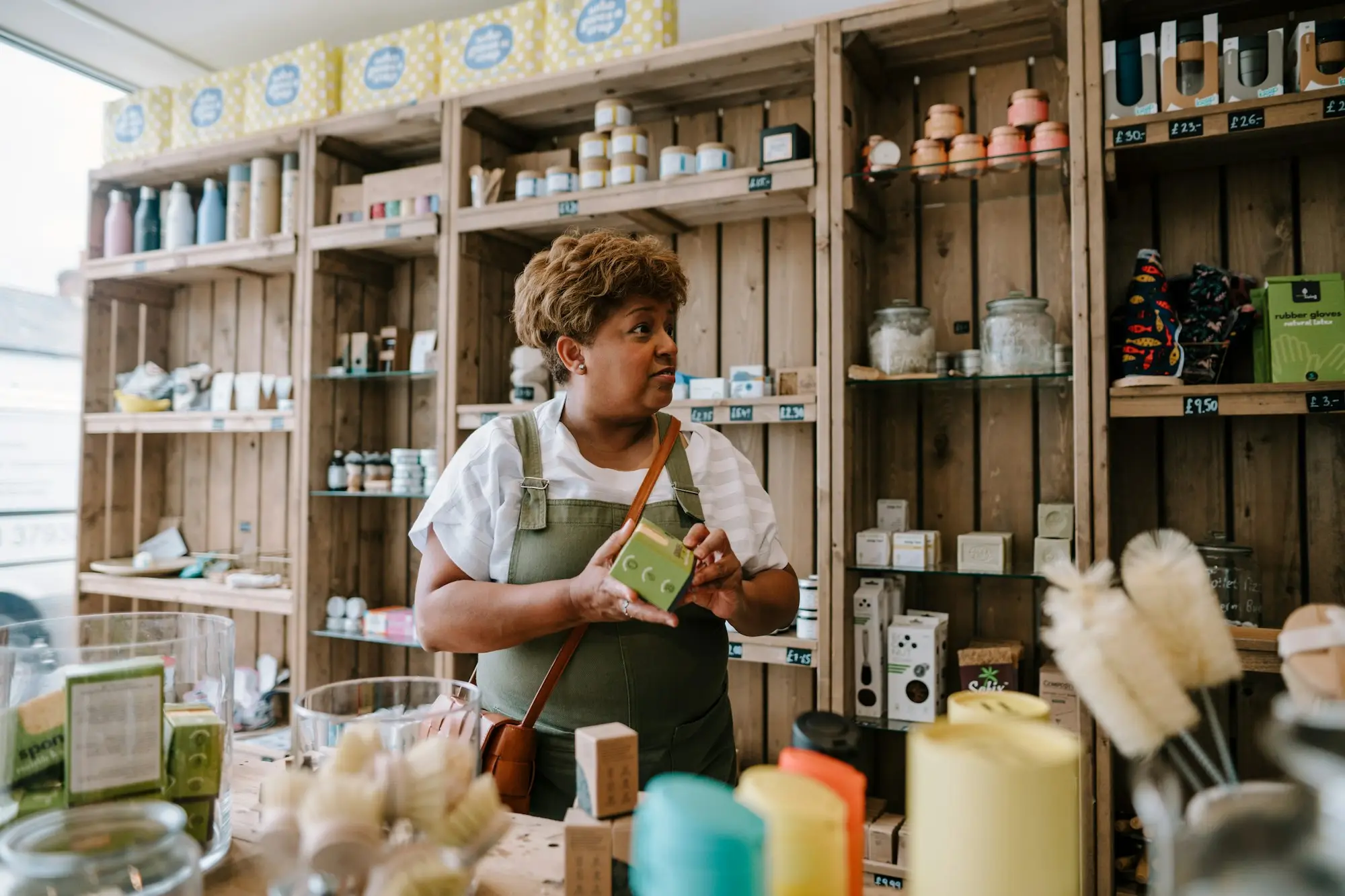 Independent boutique/homewares shop owner arranging stock on shelves